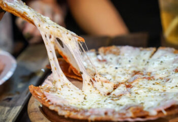 person's hand taking a slice of pizza from a pizza plate