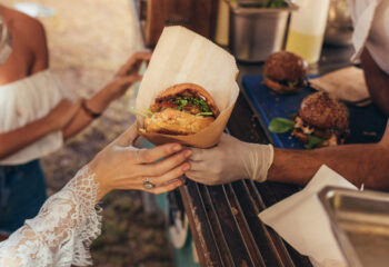 woman's hand receiving a burger from a catering food truck owner