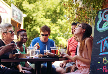 group of friends having lunch with food trucks at the background