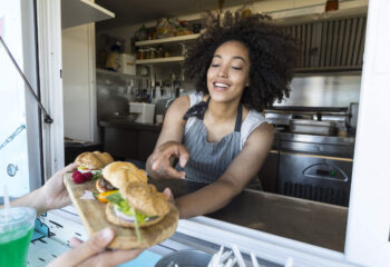 food truck owner giving an order of sandwiches and burgers to a customer