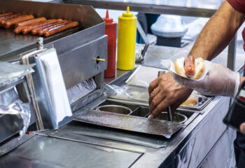 hot dog cart owner preparing a hot dog in New York City