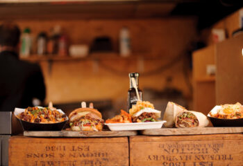 a line of burgers, fries, and burritos in a counter