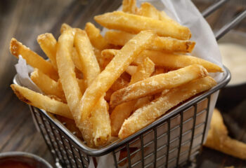 bucket of freshly cooked french fries with ranch dip on the side